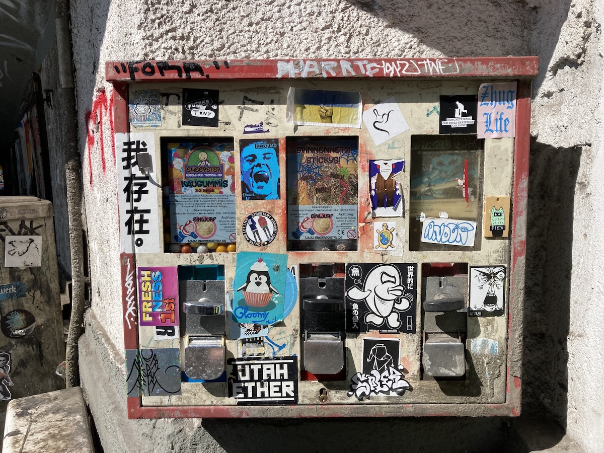 Eine vielfältige Sticker-Collage mit kleinen Motiven, Logos und Botschaften bedeckt einen Stromkasten.