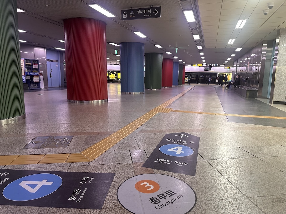 Breiter Bahnsteigbereich der Seoul Metro mit farbigen Säulen sowie Wegweisern zu den Linien 3 und 4