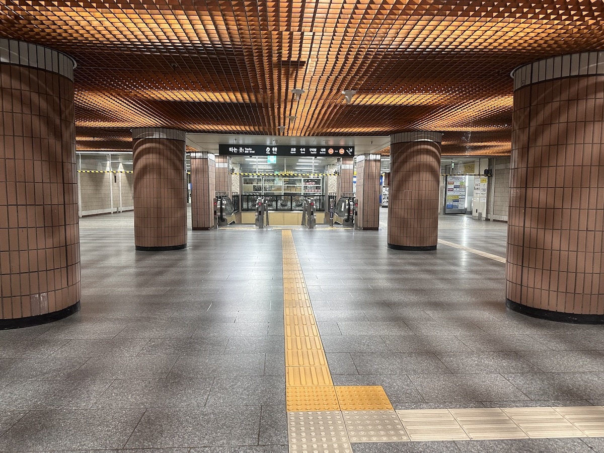 Eine weitläufige Station der Seoul Metro mit Wegweiser, Linien 3 und 4 sowie gelbem Blindenleitsystem auf dem Boden.