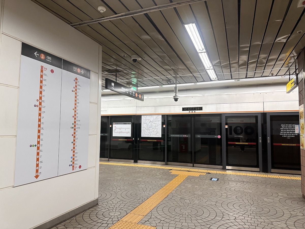 Am Bahnsteig der Seoul Metro weisen Linienpläne und ein orangefarbener Leitstreifen den Weg zu den Zügen.