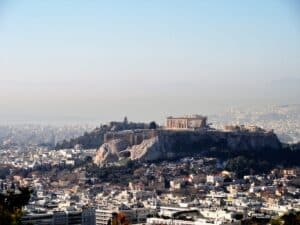 Über den Dächern von Athen erhebt sich die Akropolis mit dem Parthenon auf einem markanten Felsen im klaren Tageslicht.