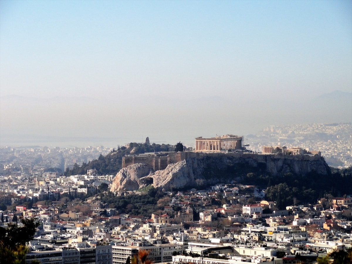 Über den Dächern von Athen erhebt sich die Akropolis mit dem Parthenon auf einem markanten Felsen im klaren Tageslicht.